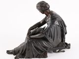 statue of a woman sitting on a stool with her legs crossed
