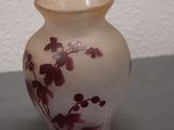 a small vase sitting on a table with a white wall behind it