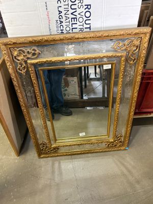a gold framed mirror sitting on the floor in a store