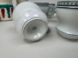 a white cup sitting on a table next to other cups