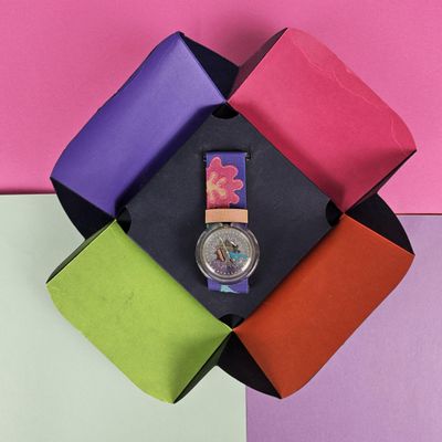 a watch sitting on top of a multicolored box