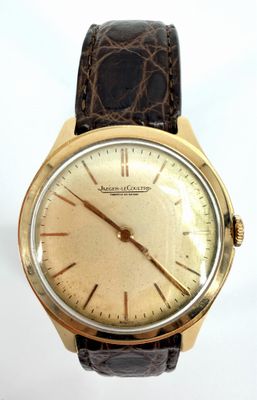 a close up of a gold watch with a brown leather strap