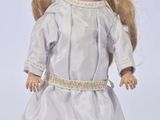 porcelain doll of a blonde haired girl in a white dress with a flower in her hair