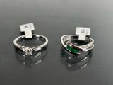 two silver rings with emerald stones on them sitting on a table