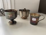three silver cups sitting on a table next to each other