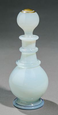 un vase en verre blanc orné d'un couvercle doré, posé sur une table