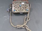 un vieux sac à main entouré d'une corde, posé sur une table