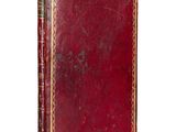 an old book with a red cover sitting on top of a white surface