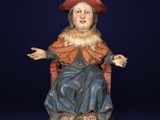 an old statue of a woman sitting on a chair with her hands out