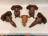 six figurines en bois sculpté posées sur un plan de travail blanc