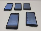 four cell phones are lined up on a white table