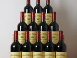 Six bouteilles de vin rouge sont empilées sur une table en bois.