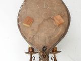 a wall clock hanging on the wall with two candles