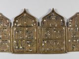 trois tentures murales en métal doré aux motifs ouvragés accrochées à un mur blanc