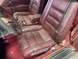 a dirty red car with leather seats in the back of it