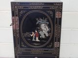 une photo d'une armoire noire sur laquelle est accrochée une peinture
