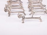 three silver dog brooches on a white background