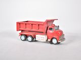 un camion jouet rouge posé sur une surface blanche