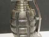 a small metal grenade shaped object on a white table