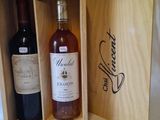 two bottles of wine in a wooden box on a bed