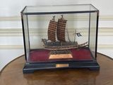 a miniature model of a chinese ship in a glass case