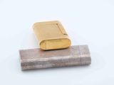 a close up of a gold lighter on a white surface