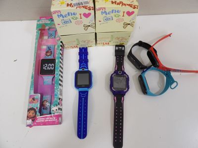 Plusieurs montres pour enfants et une paire de ciseaux sont posés sur une table