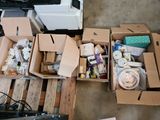 Plusieurs cartons contenant des articles divers sont posés sur une palette dans un garage.