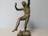 statue d'un homme assis sur un rocher, tenant une balle dans la main
