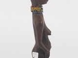 a wooden statue of a woman with a beaded head