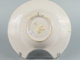 underside view of a white porcelain bowl on a stand on a gray surface