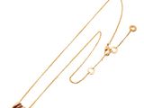 a close up of a gold necklace with a ball on a chain