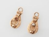 a pair of gold earrings with pearls on them on a white surface