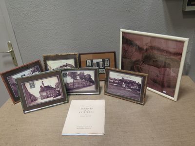 a lot of framed pictures on a table with a book