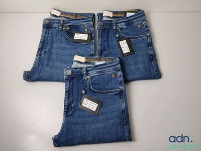trois paires de jeans, encore étiquetées, posées sur une table