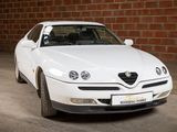 a white car that is parked in front of a brick wall