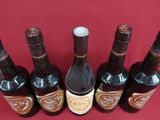 six bottles of wine are lined up in a row on a red surface