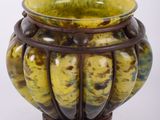 un vase jaune et marron posé sur une surface blanche