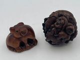 two small wooden animals sitting next to each other on a white surface