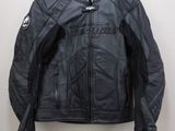 une veste de moto en cuir noir suspendue à un cintre accroché au mur