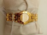 a gold watch sitting on a pillow next to a mirror