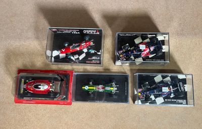 four toy cars are in boxes on a carpeted surface