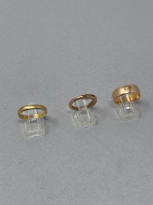trois bagues en or et une bague posée sur un socle transparent