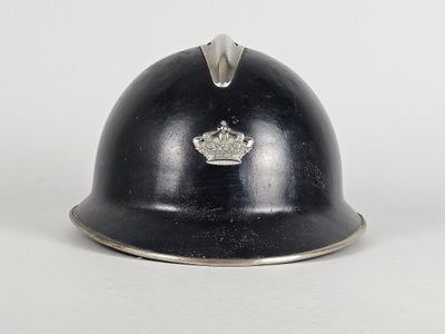 un vieux casque orné d'une couronne, posé sur une surface blanche