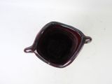 a red bowl with a black lid on a white table