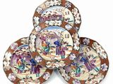 four plates with a picture of people on them on a white surface