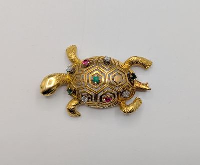 a close up of a gold turtle brooch with colorful stones