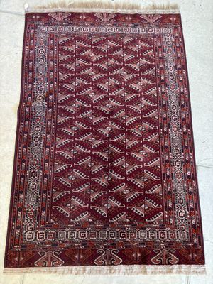 un tapis rouge à motifs posé sur un sol blanc