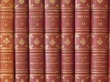 several red books are lined up on a shelf in a row