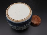a blue and white cup with a brown lid next to a penny